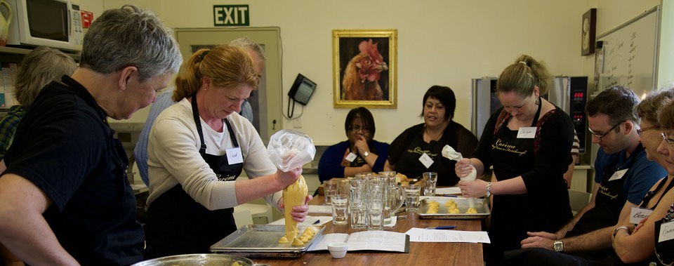 Students pipe profiteroles in a cooking class with Jo Crabb