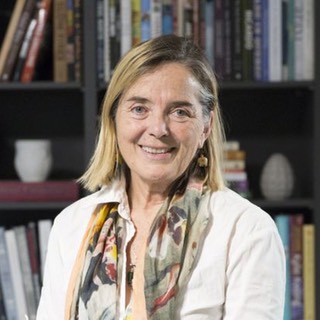 Portrait of Naomi Duguid sitting in front of bookshelves