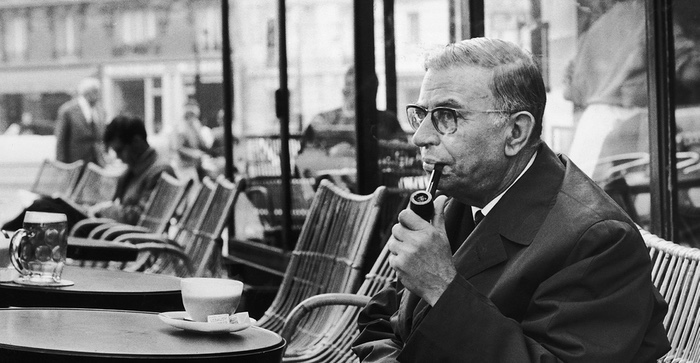 John Paul Sartre smokes a pipe and drinks a coffee in Paris