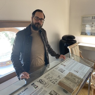 Matteo Ghirigini in front of a display case housing a copy of Bartolomeo Scappi's original cookbook of 1570