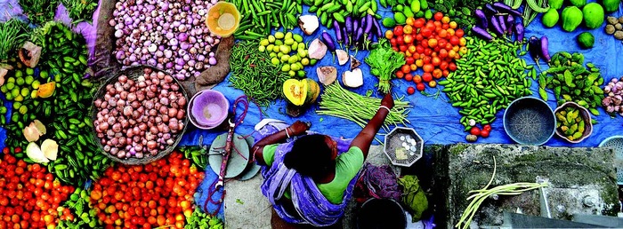 A woman in Western Bangladesh offers a range of fruits and gegetables for sale