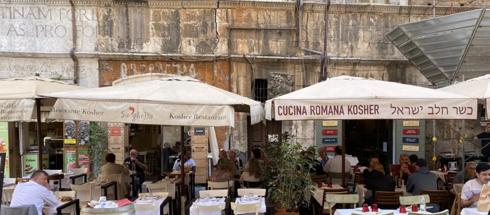 Outdoor dining in the former ghetto of Rome with restaurants advertising typical Jewish cuisine in Italian and Ivrit