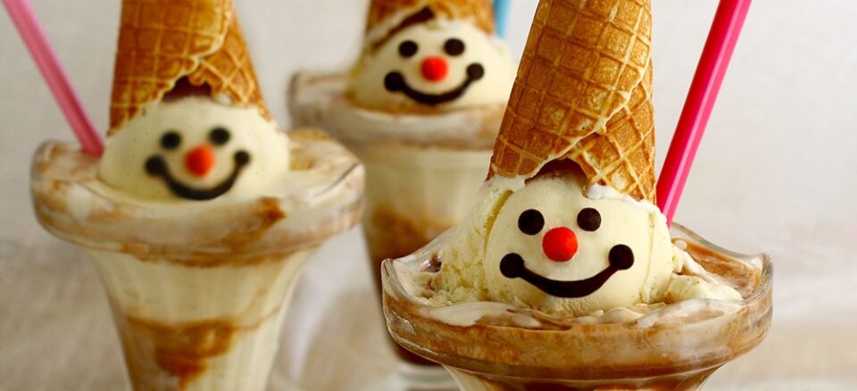Three ice-cream sundaes with smiley faces painted on them in chocolate