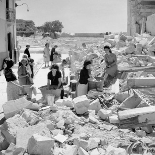 Black and white photo of Maltese women washing clothes in the rubble of their houses in June 1942
