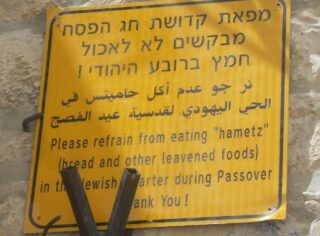 A sign in Jerusalem in Hebrew, Arabic and English. The English text reads: Please refrain from eating "Chametz" (bread and other leavened foods)in the Jewish quarter during Passover. Thank you!